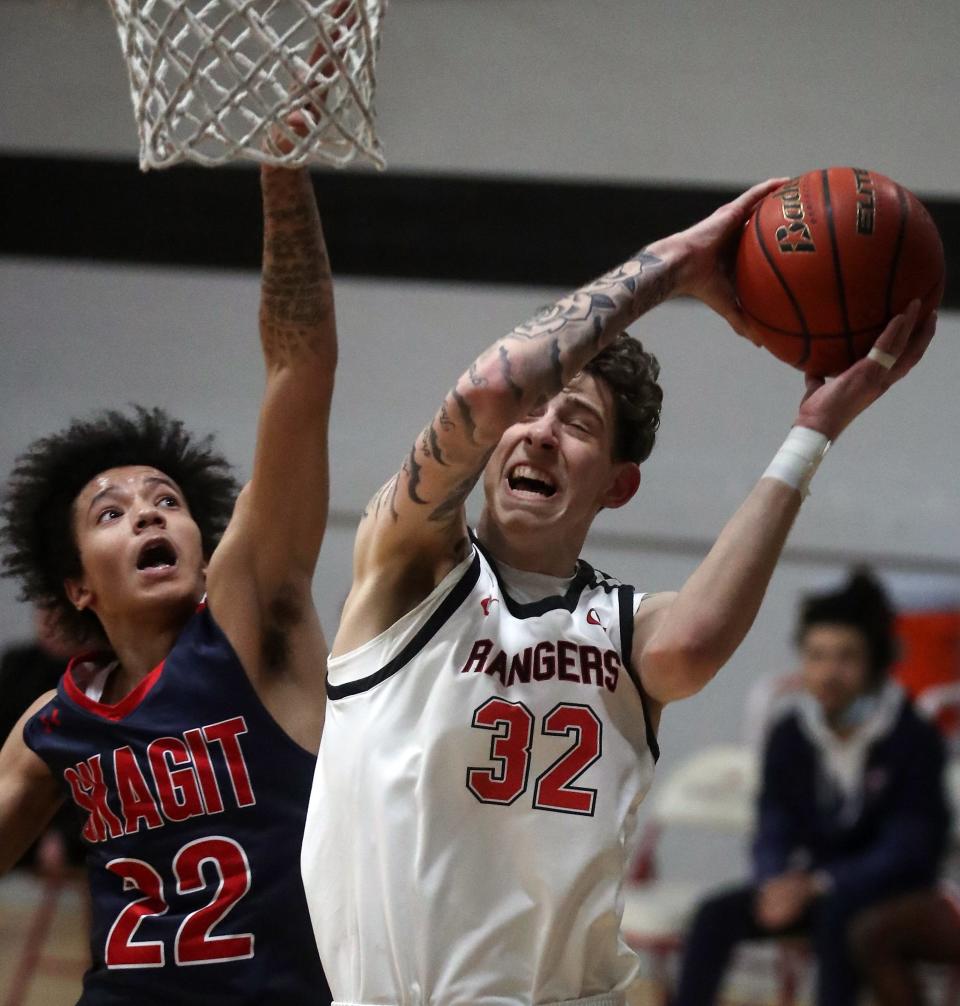 Skagit Valley's Hodges Fleming (22) tries to get a hand on the ball as Olympic College's Tyler Behrend (32) goes up for a basket during their game on Wednesday, March 9, 2022.