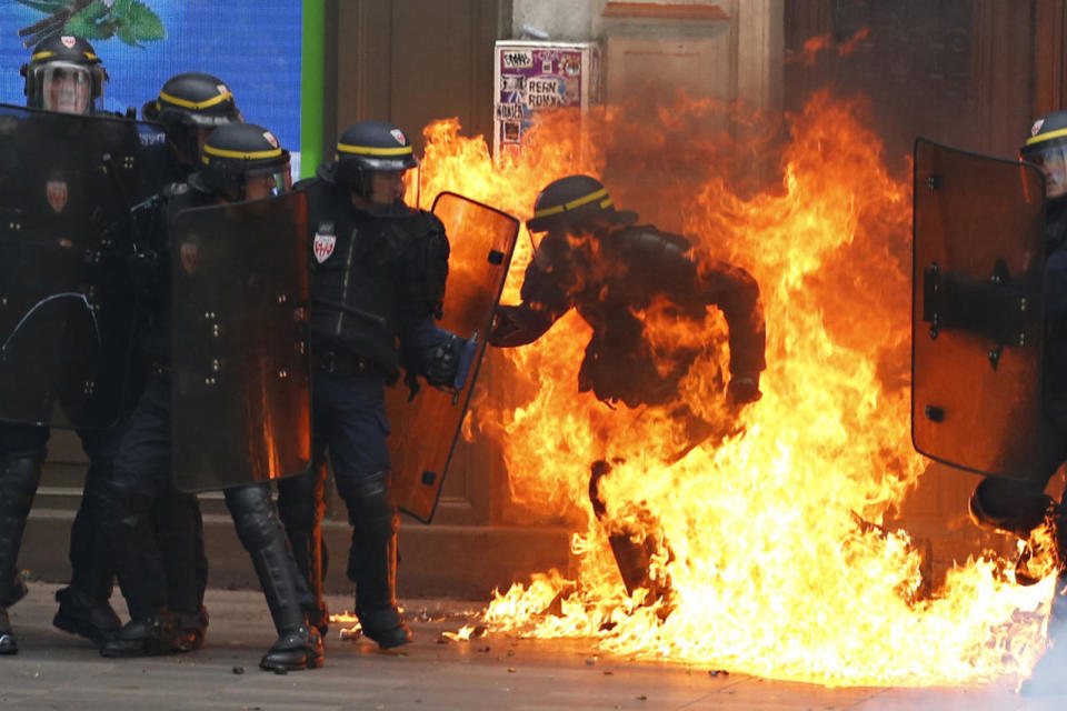 French riot police officer is surrounded by flames