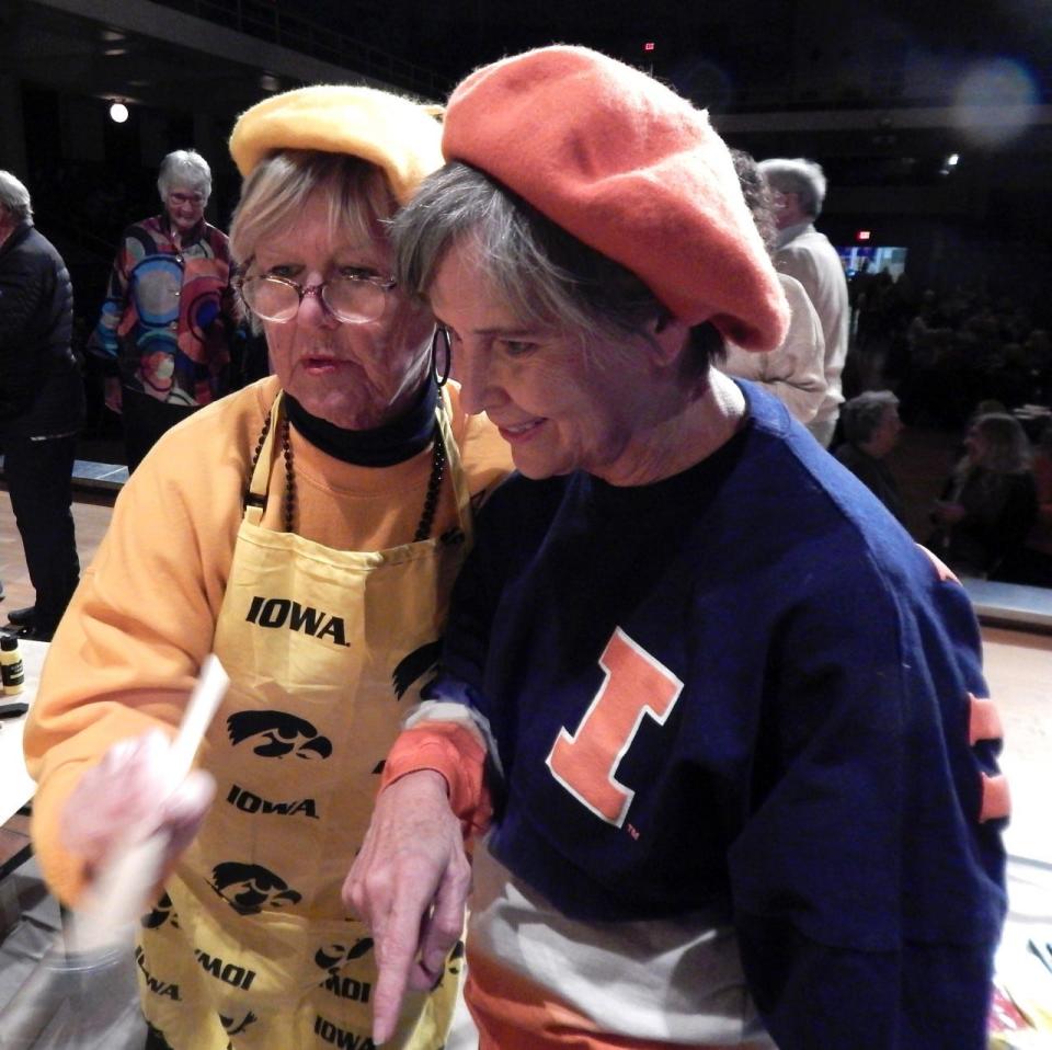 Artist Kim Staub, left, and coach Janet Hachmeister discuss Staub’s pop art masterpiece at the 2022 Celebrity Battle of the Brushes paint-off held at Burlington Memorial Auditorium on Friday, Nov. 18, 2022. Staub's painting sold for $3,000 at the event to raise money for the Art Center of Burlington.