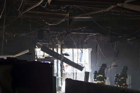 Firefighters enter a CVS pharmacy on the corner of W North Avenue and Pennsylvania Avenue, a day after it was looted and set ablaze in protest for the death of 25-year-old black man Freddie Gray who died in police custody in Baltimore, Maryland April 28, 2015. REUTERS/Adrees Latif