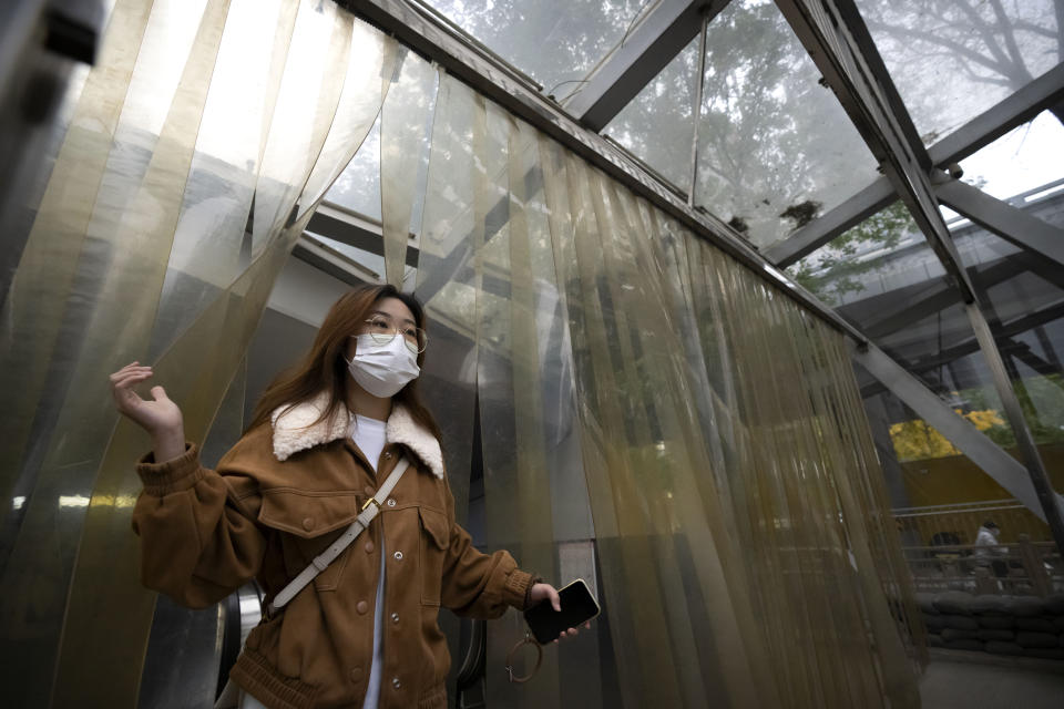 A commuter wearing a face mask walks out of a subway station in the central business district in Beijing, Friday, Oct. 28, 2022. (AP Photo/Mark Schiefelbein)