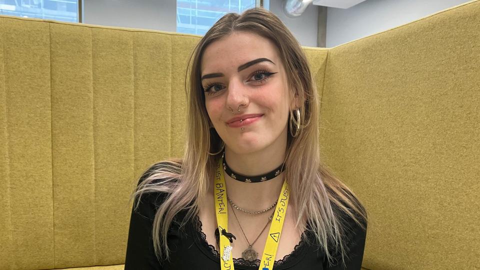 A young blonde female student sitting on a yellow chair