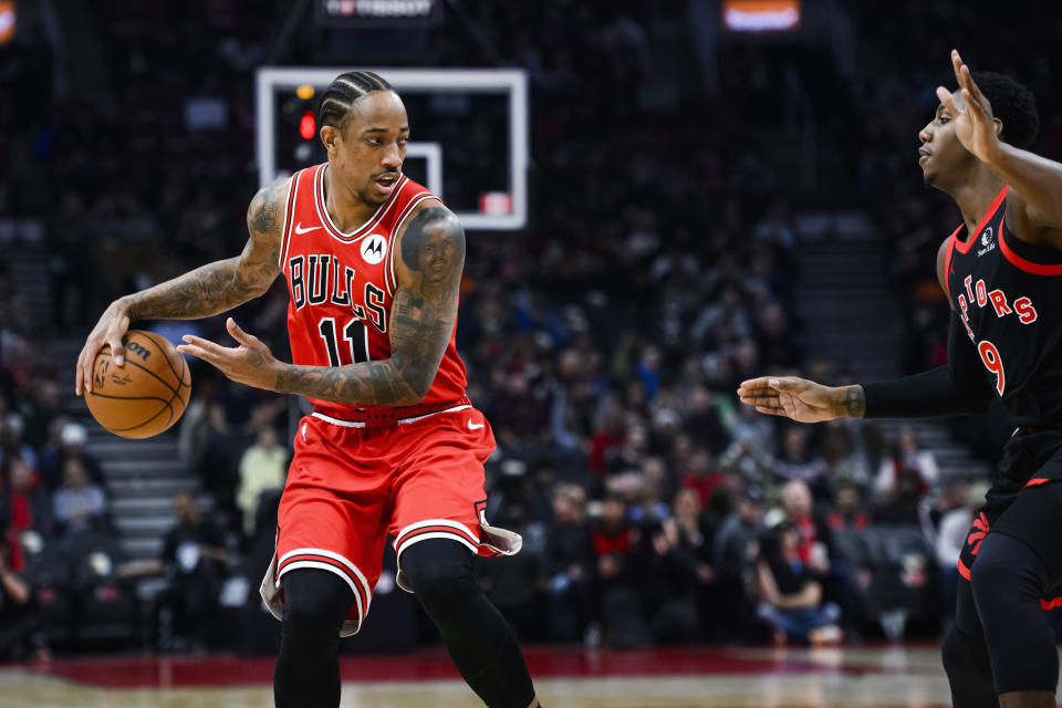 Chicago Bulls forward DeMar DeRozan (11) passes the ball behind his back while Toronto Raptors guard RJ Barrett (9) defends during the first half of an NBA basketball game Thursday, Jan. 18, 2024, in Toronto. (Christopher Katsarov/The Canadian Press via AP)