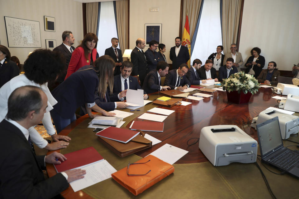 The leader of the Catalonian ERC party Oriol Junqueras, 3rd right, councilor Josep Rull, 5th right, and Jordi Sanchez, president of the Catalan National Assembly, 4th left, sign documents inside the Spanish parliament in Madrid, Spain, Monday May 20, 2019. The five separatist leaders on trial for Catalonia's 2017 secession attempt who were elected to the Spanish Parliament in April 28 elections have been escorted by police to pick up their official parliament credentials. The Supreme Court is allowing the five politicians to get their credentials on Monday and attend the opening session of the new Parliament on Tuesday. (J.J. Guillen/Pool Photo via AP)