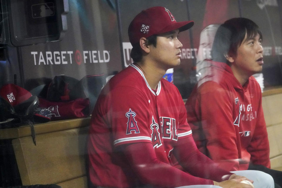 Los Angeles Angels' Shohei Ohtani, left, and his interpreter watch the sixth inning from the dugout as Ohtani did not play against the Minnesota Twins in a baseball game Friday, July 23, 2021, in Minneapolis. The Twins won 5-4. (AP Photo/Jim Mone)