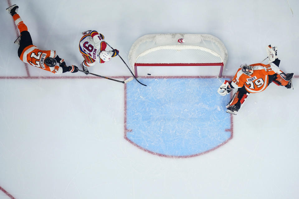 New Jersey Devils' Dawson Mercer (91) scores a goal against Philadelphia Flyers' Tony DeAngelo (77) and Carter Hart (79) during an NHL hockey game, Saturday, Dec. 3, 2022, in Philadelphia. (AP Photo/Matt Slocum)