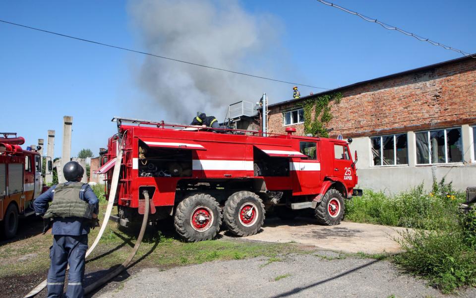 A firefighter stands by a fire engine at a warehouse in an industrial area affected by a fire that started after the shelling of Russian troops, Kharkiv, northeastern Ukraine - Shutterstock