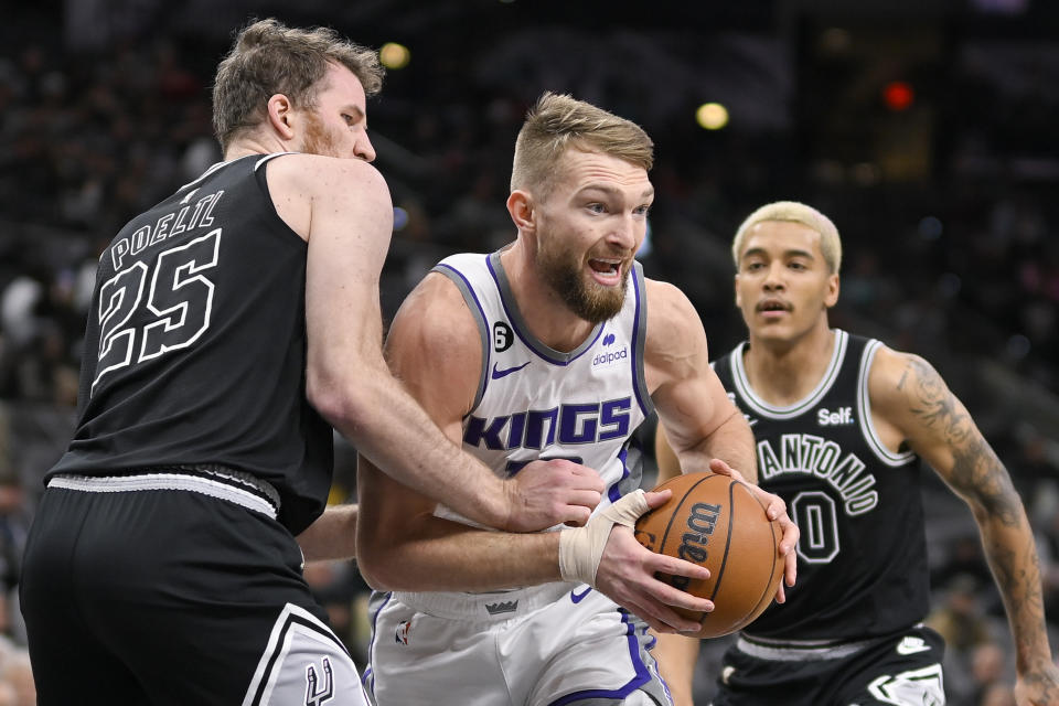 Sacramento Kings' Domantas Sabonis, center, drives between San Antonio Spurs' Jakob Poeltl (25) and Jeremy Sochan during the first half of an NBA basketball game, Wednesday, Feb. 1, 2023, in San Antonio. (AP Photo/Darren Abate)