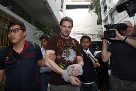 Hans Fredrik Lennart Neij (C), a co-founder of the Swedish file-sharing website, The Pirate Bay, is escorted by Thai police officers as he arrives at the Immigration Detention Center in Bangkok November 5, 2014. REUTERS/Chaiwat Subprasom