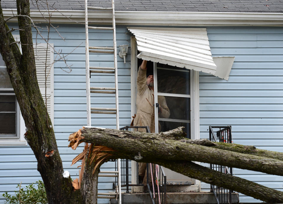 Harold Grant tries to repair his front door awning before cutting up a tree that broke in his front yard after a tornado touched down, damaging 25 homes and knocking out power Wednesday, Jan. 30, 2013, in Ashland City, Tenn. Around 25 homes in Ashland City had minor damage. (AP Photo/Mark Zaleski)