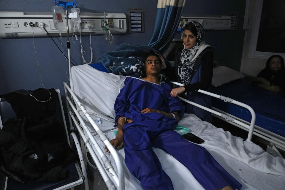 Mohammad Mehdi Ghalekhani, left, a member of Basij paramilitary force, who was wounded in Wednesday's bomb explosion lies on bed as his sister Fatemeh stands next to him at Bahonar hospital in the city of Kerman about 510 miles (820 kms) southeast of the capital Tehran, Iran, Thursday, Jan. 4, 2024. Investigators believe suicide bombers likely carried out an attack on a commemoration for an Iranian general slain in a 2020 U.S. drone strike, state media reported Thursday, as Iran grappled with its worst mass-casualty attack in decades and as the wider Mideast remains on edge. (AP Photo/Vahid Salemi)