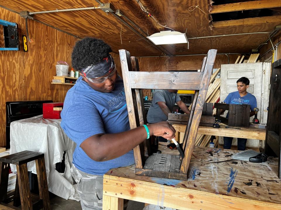 Joshua Golden (left) stains a wooden stoll at the carpentry station at Project LIFT Fort Pierce on Aug. 11.