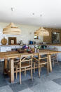 <p> If the table is the heart of your country kitchen diner, it&apos;s a smart idea to make it the star of the show. Here, the U-shape of the cabinets frames the dining table, with low-slung pendant lights putting it firmly in the spotlight. </p> <p> For a do-anything table like this, which functions as a work surface, dining area, desk and gathering space, it&apos;s essential to clear it of clutter between each task. Simply leave a basket or bowls of fruit and fresh flowers to bring the country look to your kitchen diner heartland. </p>