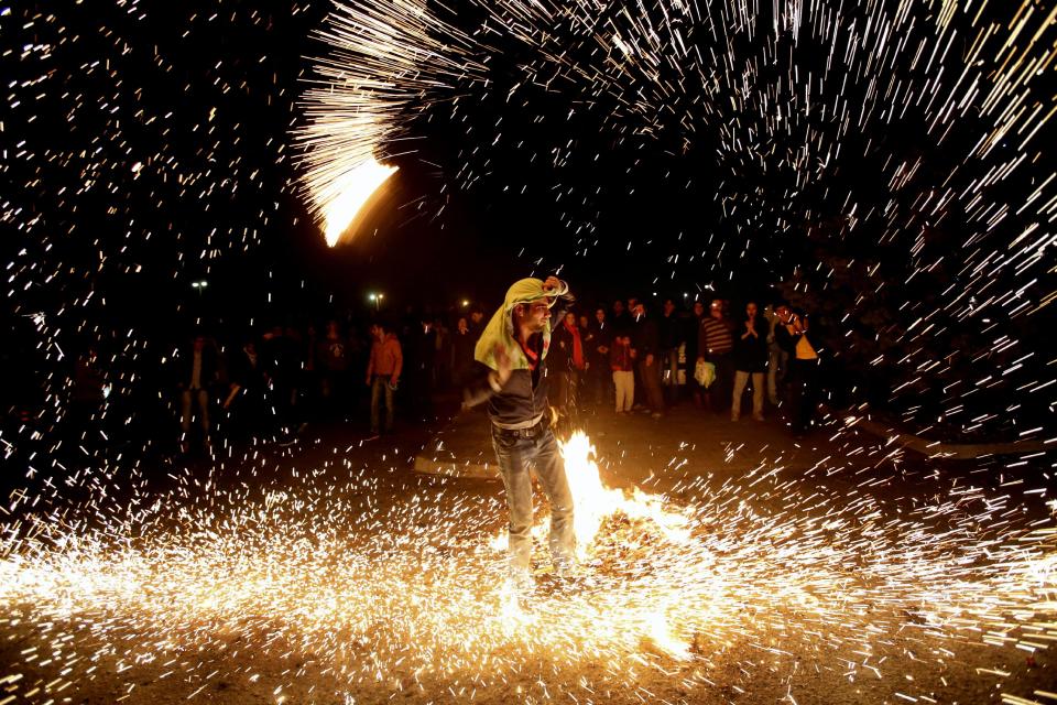 In this picture taken on Tuesday, March 18, 2014, an Iranian man lights fireworks during a celebration, known as “Chaharshanbe Souri,” or Wednesday Feast, marking the eve of the last Wednesday of the solar Persian year, in Pardisan park, Tehran, Iran. The festival has been frowned upon by hard-liners since the 1979 Islamic revolution because they consider it a symbol of Zoroastrianism, one of Iran’s ancient religions of Iranians. They say it goes against Islamic traditions. (AP Photo/Vahid Salemi)