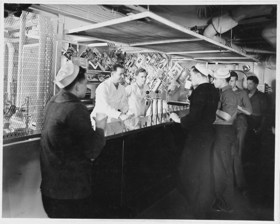 Sailors gather around a soda fountain and ice cream parlor aboard USS Brooklyn (CL-40).