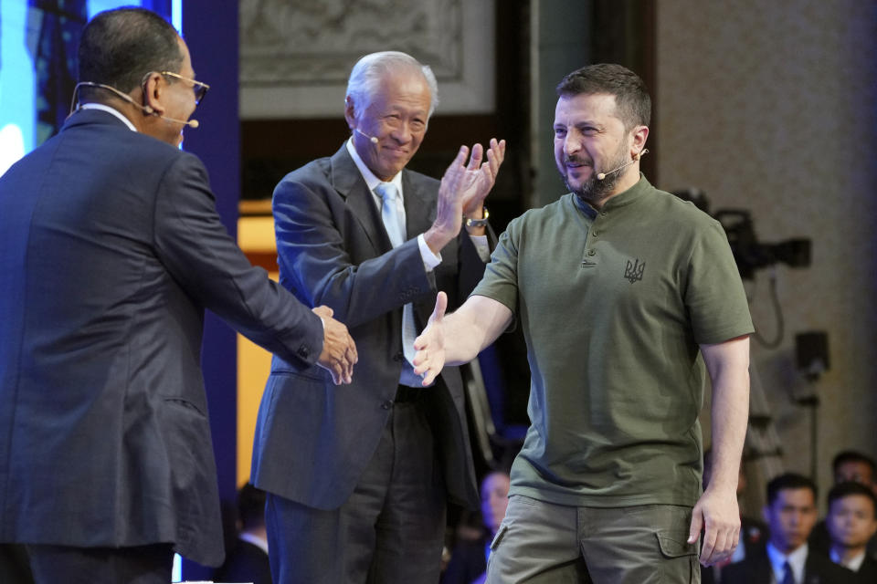 Ukraine's President Volodymyr Zelenskyy, right, shakes hand with Malaysian Defense Minister Mohamed Khaled Nordin, left, and Singaporean Defense Minister Ng Eng Hen before speaking during the 21st Shangri-La Dialogue summit at the Shangri-La Hotel in Singapore, Sunday, June 2, 2024. (AP Photo/Vincent Thian)