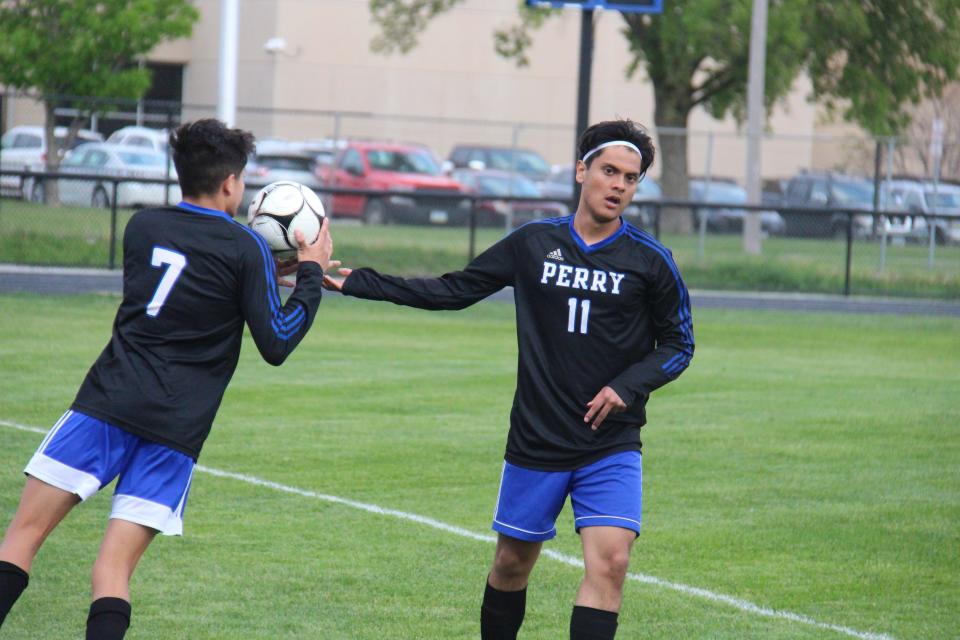 Perry's Sergio Sanchez hands the ball to Anthony Chavez on the sidelines during the substate semifinal on Monday, May 23, 2022, in Perry.