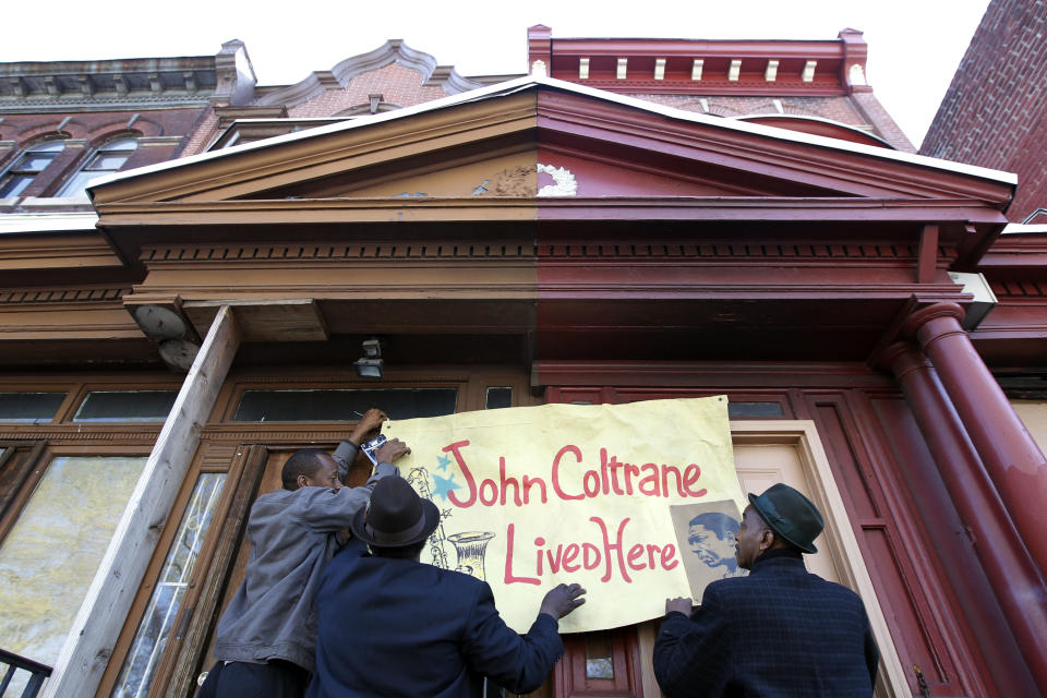 Men hang a banner on the former home, left, of jazz musician John Coltrane Friday, April 13, 2012, in Philadelphia. Jazz lovers and cultural officials in Philadelphia are promoting a fundraising effort to save the run-down house. Coltrane lived in a rowhouse in the city's Strawberry Mansion neighborhood from 1952 to 1958. (AP Photo/Matt Rourke)