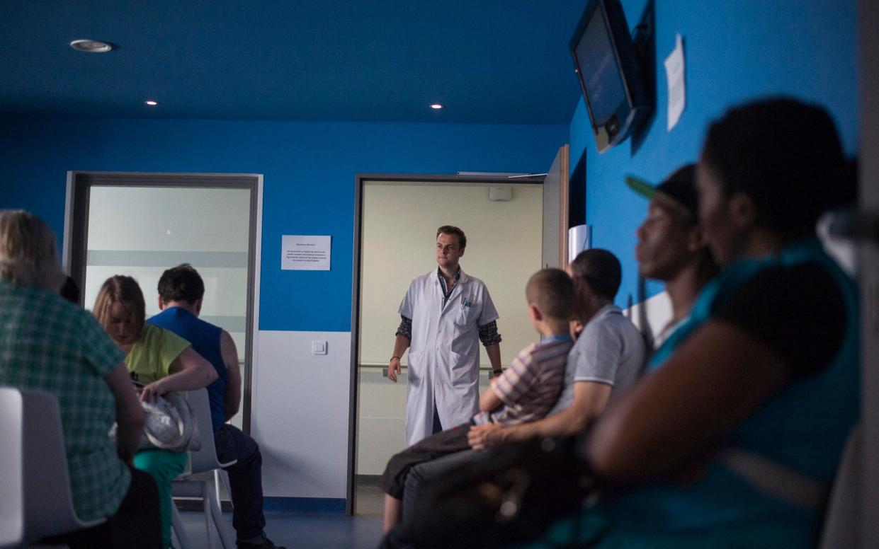 A doctor calls a patient in the waiting room at the surgery consultation at Argenteuil hospital, north of Paris