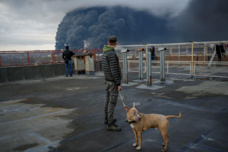 TOPSHOT - A man stands with his dog as smoke rises after an attack by Russian army in Odessa, on April 3, 2022. - Air strikes rocked Ukraine's strategic Black Sea port Odessa early Sunday morning, according to an interior ministry official, after Kyiv had warned that Russia was trying to consolidate its troops in the south. (Photo by BULENT KILIC / AFP) (Photo by BULENT KILIC/AFP via Getty Images)