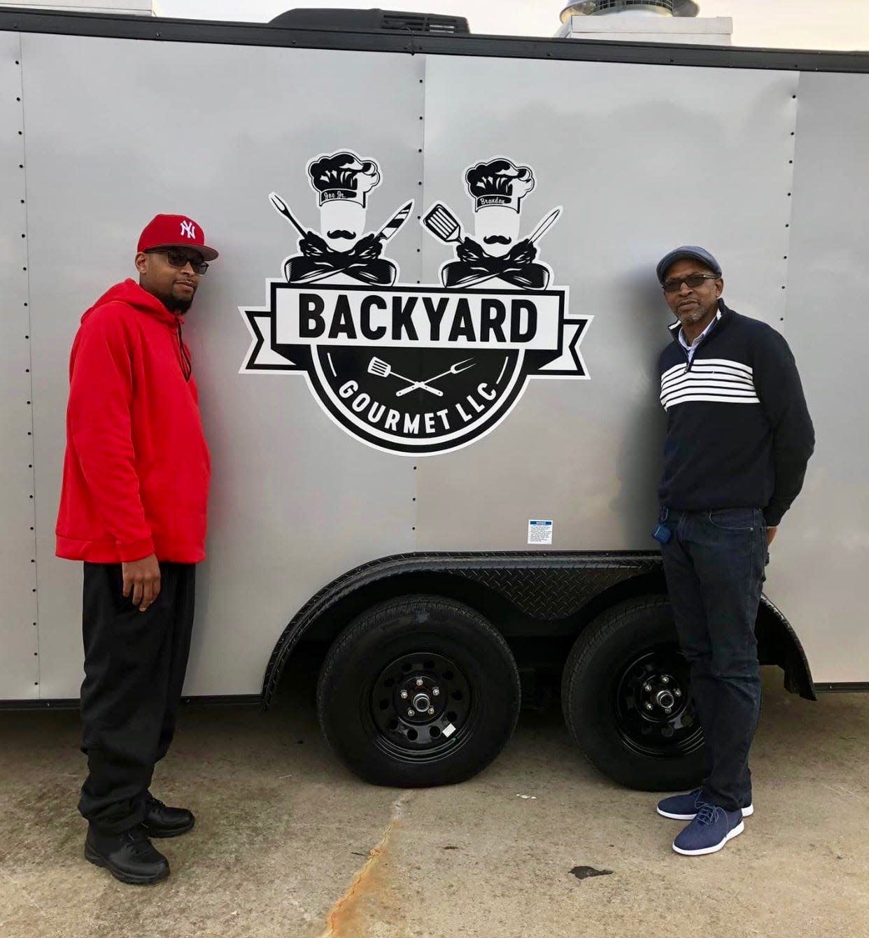 Brandon Dell Curry and his father Joseph Walker, Jr. stand in front of Curry's custom made food truck, Brandon Curry's Backyard Gourmet LLC, in 2020.