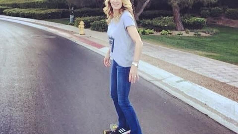 Stefi Graff in blue jeans and grey t-shirt riding a skateboard