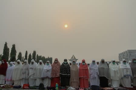 Indonesian Muslim women pray for rain during a long drought season and haze in Pekanbaru