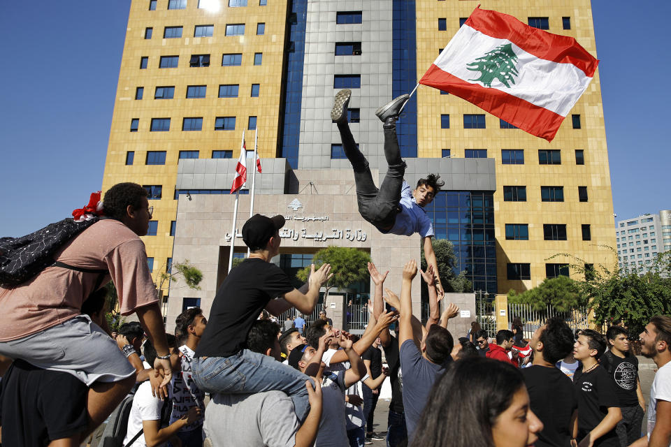 A student protester is thrown into the air by his colleagues as he holds a Lebanese flag during ongoing protests against the Lebanese government, in front of the education ministry in Beirut, Lebanon, on Nov. 12, 2019. | Bilal Hussein—AP