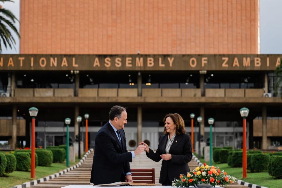 Doug Emhoff accepts a pen from Kamala Harris in front of the National Assembly of Zambia