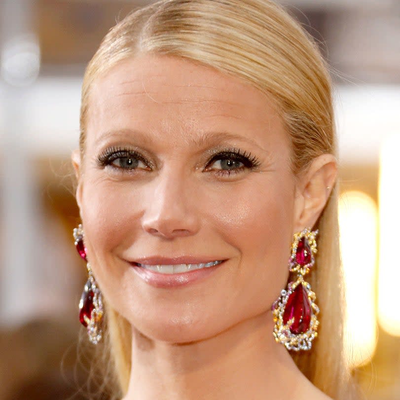 Woman with elegant earrings and styled hair, smiling at an event