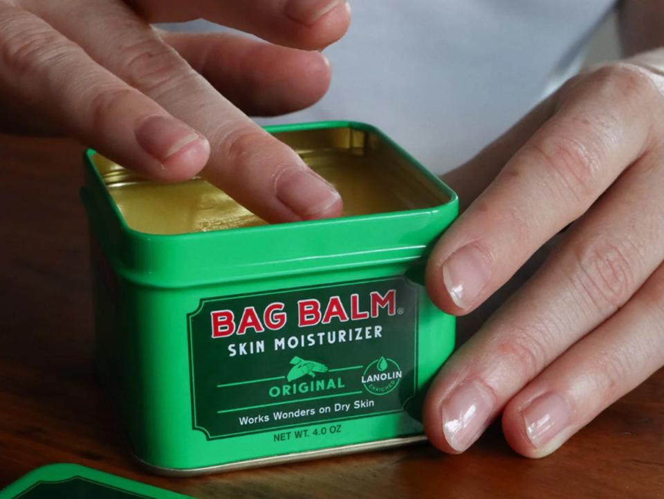 A hand dips into a tin of Vermont’s Original Bag Balm skin moisturizer (Vermont’s Original Bag Balm)