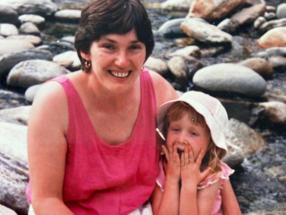 A mom and daughter sitting on a pebble beach