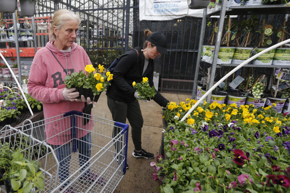 Gail Henrickson, left, and her daughter, Melissa, shop for plants at a local garden center as they stay at home during the coronavirus outbreak Monday March 23 , 2020, in Richmond, Va. The two work at a local restaurant that has closed down and are doing their spring gardening. (AP Photo/Steve Helber)