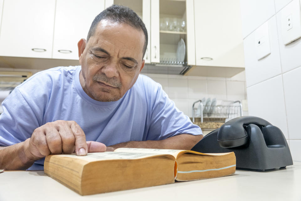 o homem lê a lista telefônica com um telefone na mesa