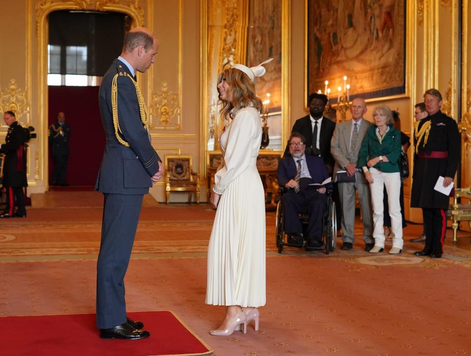 Kate Garraway, from London, is watched by her husband Derek Draper as she is made a Member of the Order of the British Empire by the Prince of Wales at Windsor Castle. The honour recognises services to broadcasting, to journalism and to charity. Picture date: Wednesday June 28, 2023.