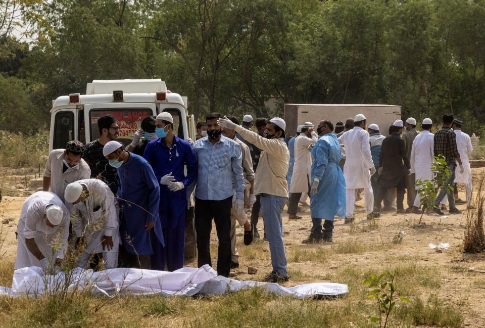 People look at the body of a man who died from the coronavirus disease as another body is carried in for burial at a cemetery in New Delhi, India, April 16, 2021. / Credit: DANISH SIDDIQUI/REUTERS