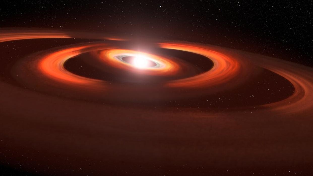  This illustration is based on Hubble Space Telescope images of gas and dust discs encircling the young star TW Hydrae. We have an oblique view of three concentric rings of dust and gas. At the centre is the bright white glow of the central star. The reddish-coloured rings are inclined to each other and are therefore casting dark shadows across the outermost ring. 