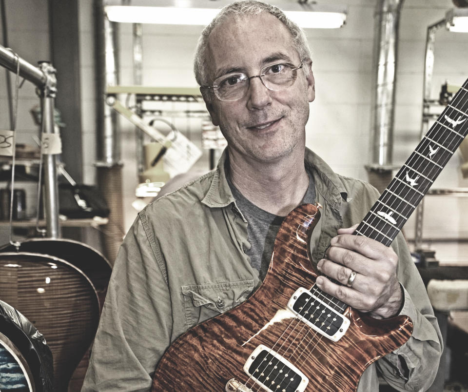 Paul Reed Smith holds a PRS guitar