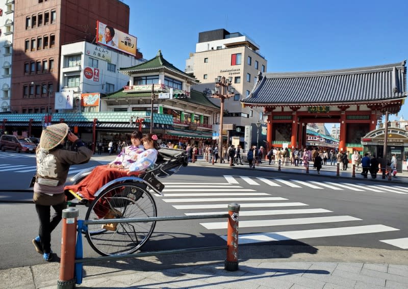 A rickshaw driver takes a souvenir photo for his clients at Asakusa district in Tokyo, Japan