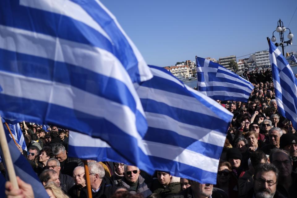 Protesters wave Greek flags during a rally outside the Municipality of Mytilene, on the northeastern Aegean island of Lesbos, Greece, on Wednesday, Jan. 22, 2020. Local residents and business owners have launched a day of protest on the Greek islands hardest hit by migration, demanding the Greek government ease severe overcrowding at refugee camps. (AP Photo/Aggelos Barai)