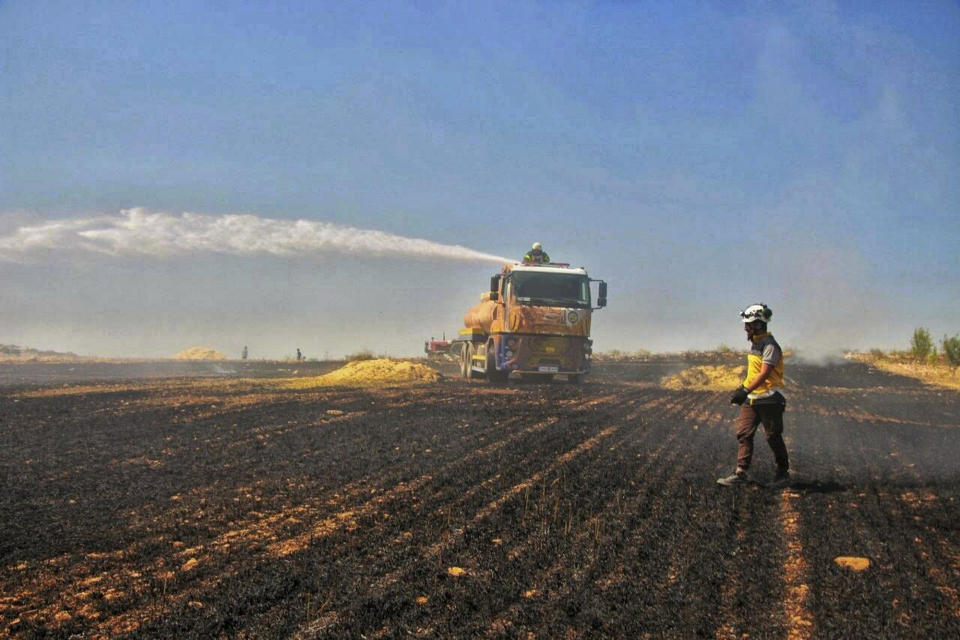 This Tuesday, May 28, 2019 photo, provided by the Syrian Civil Defense White Helmets, which has been authenticated based on its contents and other AP reporting, shows Syrian White Helmet civil defense workers trying to extinguish a fire in a field of crops, in Kfar Ain, the northwestern province of Idlib, Syria. Crop fires in parts of Syria and Iraq have been blamed on defeated Islamic State group militants in the east seeking to avenge the group’s losses, and on Syrian government forces in the west battling to rout other armed groups there. (Syrian Civil Defense White Helmets via AP)