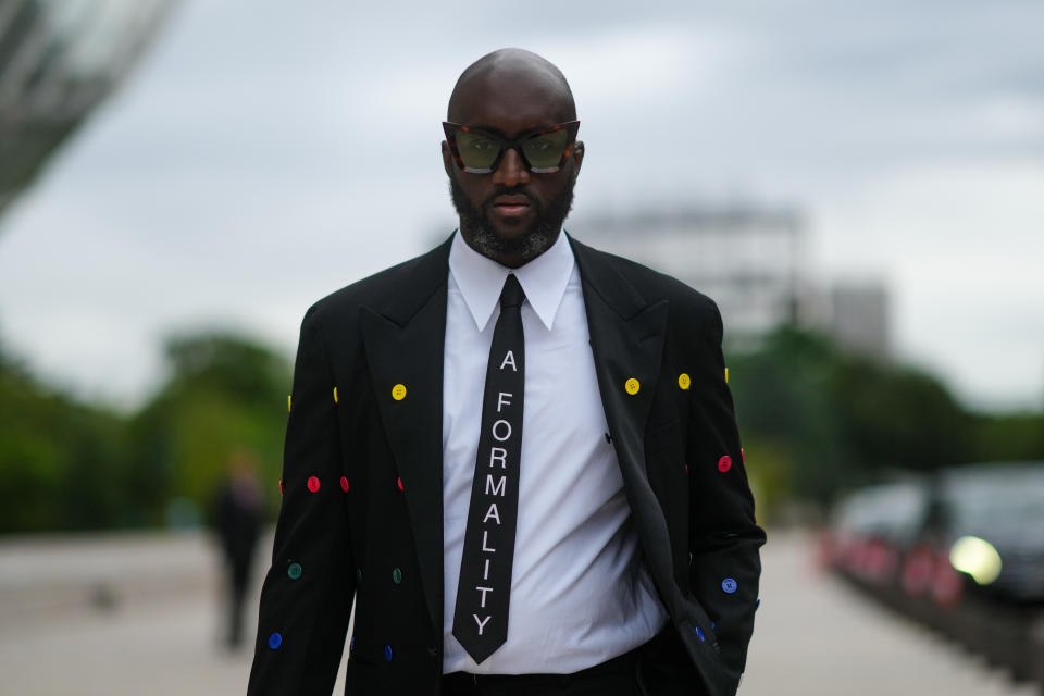 PARIS, FRANCE - JULY 05: Virgil Abloh wears a white shirt, a black tie with 'A Formality' slogan, a black blazer jacket with multicolored buttons embroidered, black flared suit pants, a gold watch, butterfly sunglasses, outside Louis Vuitton Parfum hosts dinner at Fondation Louis Vuitton, during Paris Fashion Week - Haute Couture Fall/Winter 2021/2022, on July 05, 2021 in Paris, France. (Photo by Edward Berthelot/Getty Images)