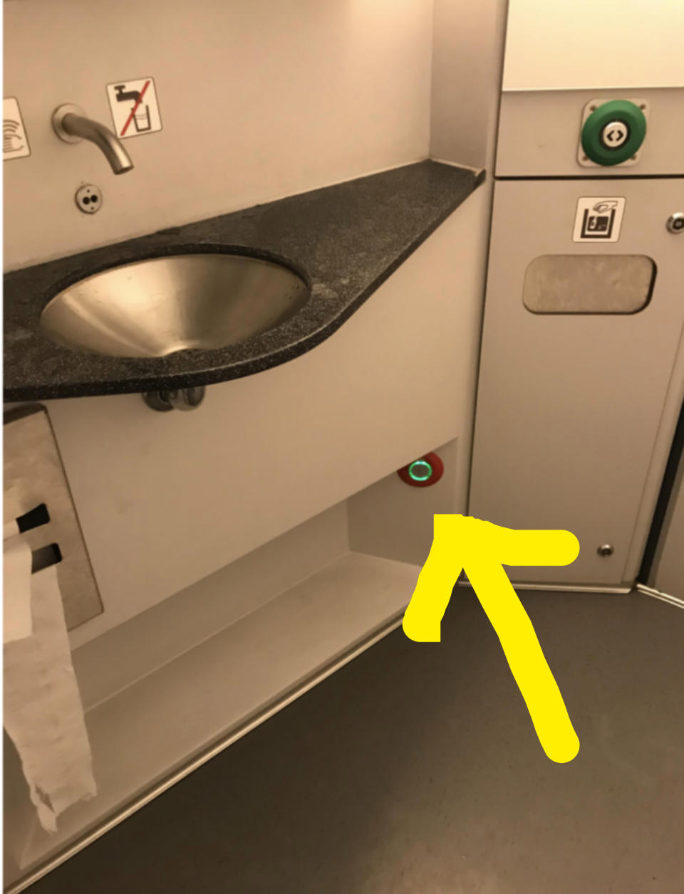 An arrow points out a button near the floor, hidden below the bathroom's sink