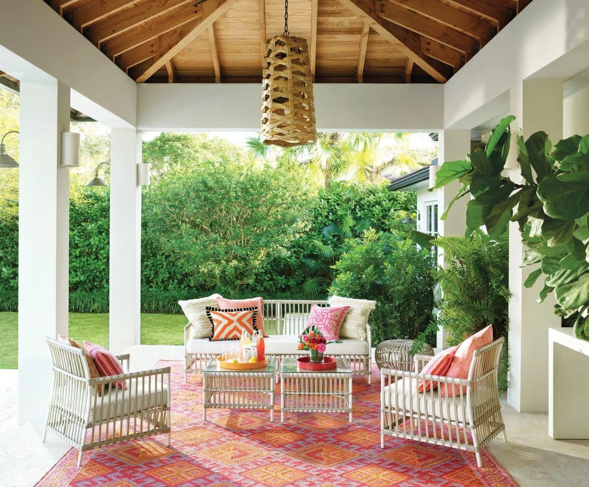 a patio with white chairs and a table with a red and white table and a white and red