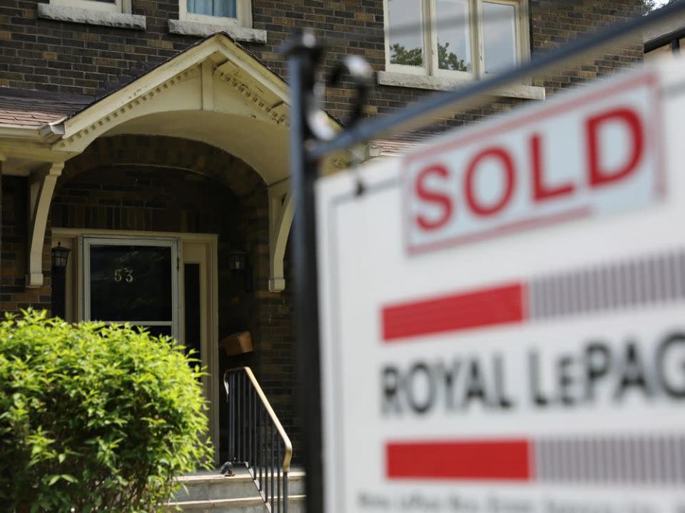 A realtor's sign stands outside a house for sale in Toronto