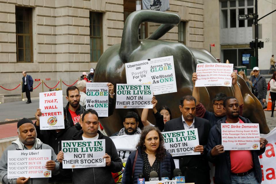 Uber drivers protest next to the Charging Bull statue in New York's financial district in May just before the company held its initial public offering. Uber's market cap is nearly $75 billion. Drivers in many major cities around the world have been trying to push the company to pay them better wages for their work.
