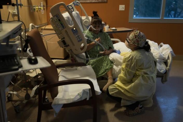 Registered nurse Nvard Termendzhyan pauses for a moment while helping Linda Calderon, a 71-year-old COVID-19 patient, sit up on her bed at Providence Holy Cross Medical Center in Los Angeles, Monday, Dec. 13, 2021. (AP Photo/Jae C. Hong)