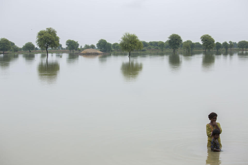 A woman stands with her child in the deep waterSaiyna Bashir/Arete/WFP