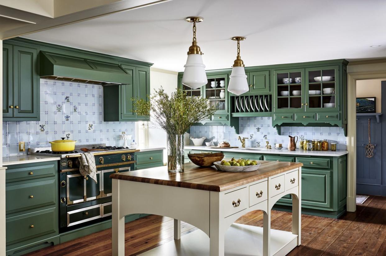 a fresh coat of green paint on this kitchens existing cabinets enlivens the whole space and plays well with the already there backsplash and countertops and a deep green range blends with the green cabinet color