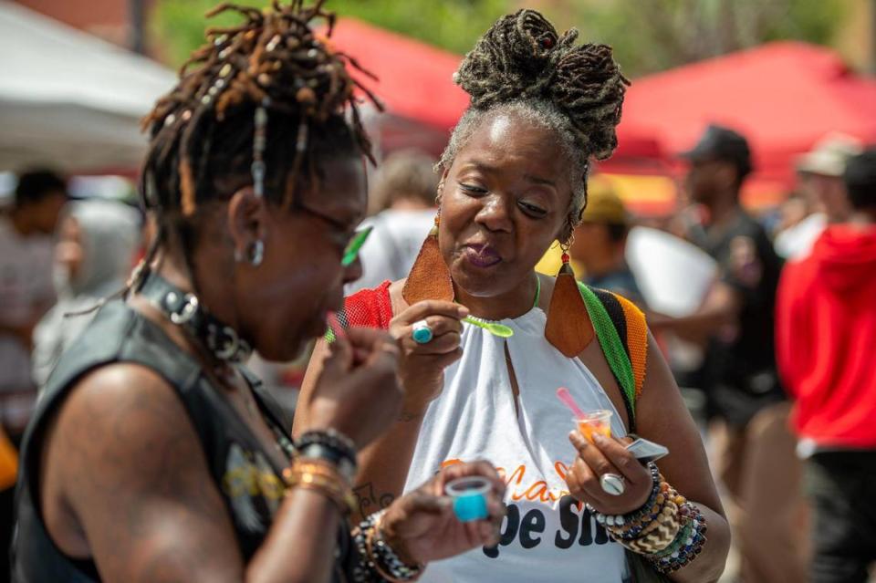 Sonya Kinsey, left, and her best friend Asura Imen try samples from the Frosty Frogs Water Ice booth during the Juneteenth KC 12th annual Heritage Festival at the18th and Vine district on Saturday, June 17, 2023, in Kansas City.